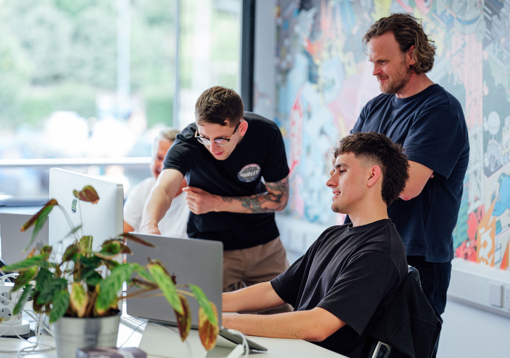 Three creatives gathered around a screen looking at design work