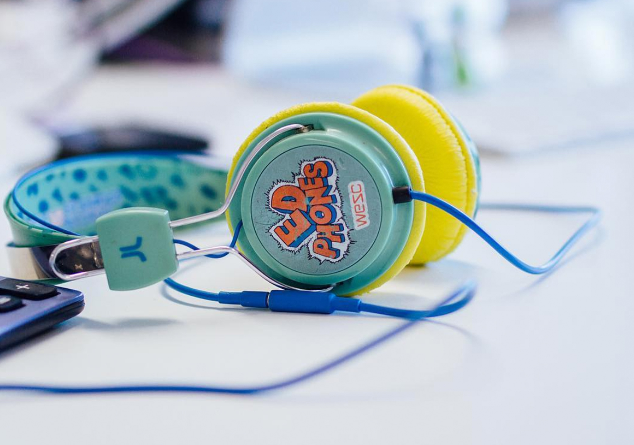 Close up photo of a pair of colourful headphones on a white desk